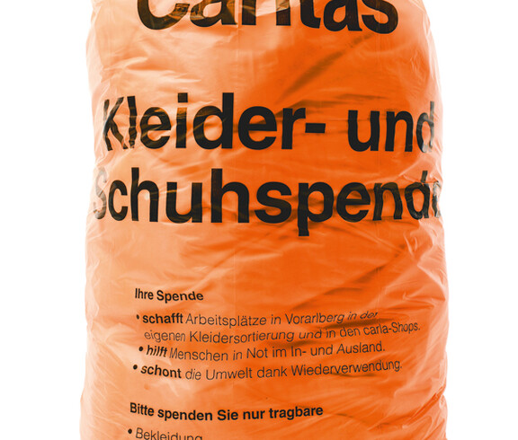 Der orange Caritas Kleidersack. Er hat Platz für zirka 8,5 Kilogramm Kleidung.